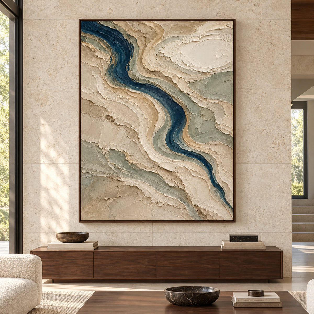 Large vertical abstract painting displayed straight-on in a bright, spacious modern room; a winding blue-green channel cuts through raised cream, sand and sage ridges.