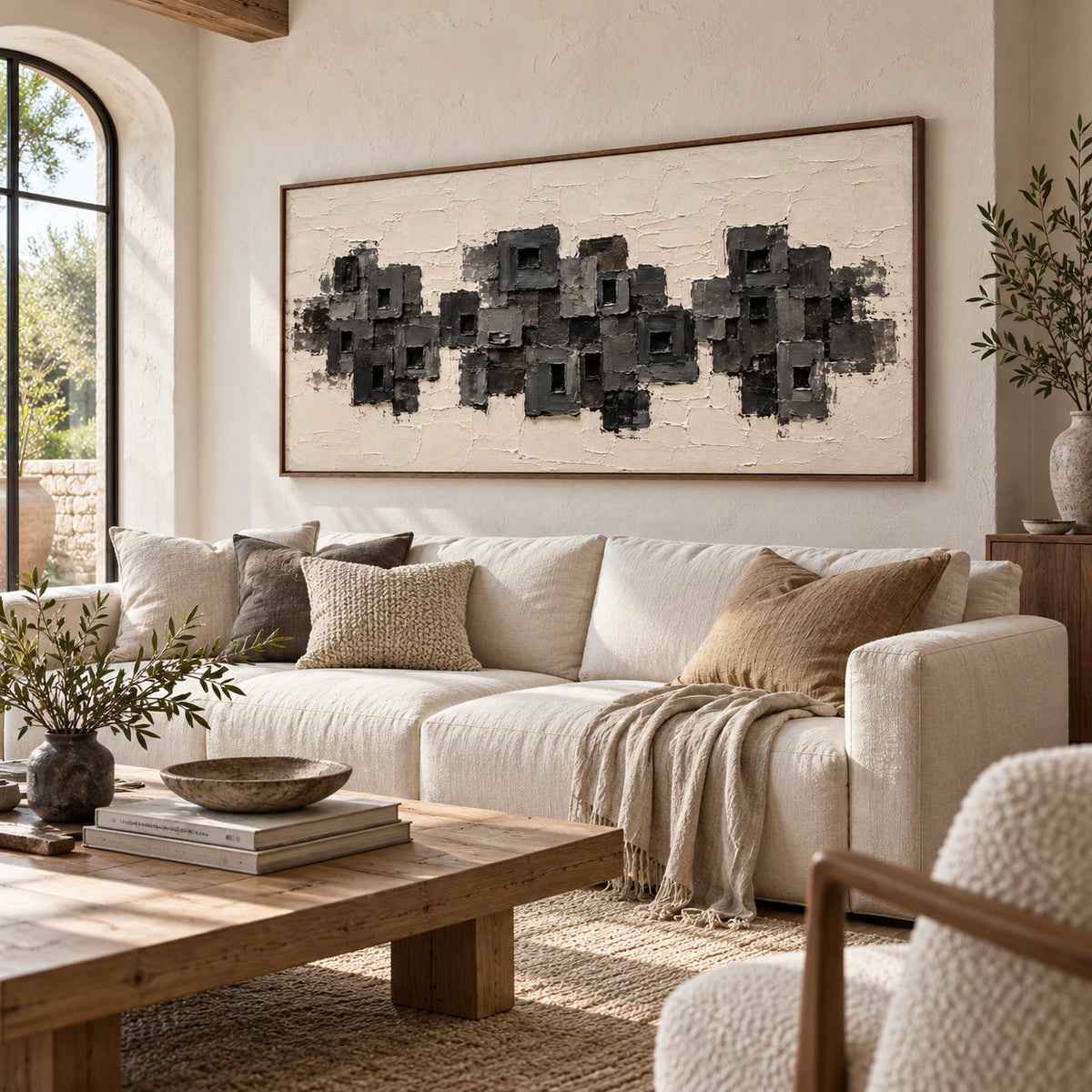 Large charcoal and ivory abstract artwork above a low sofa in a bright living room.