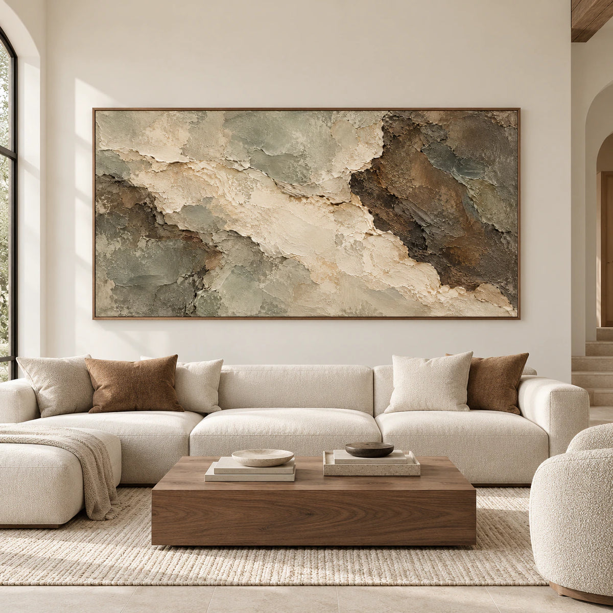 Straight-on view of a large textured abstract painting above a cream sofa in a spacious room with bright natural daylight.