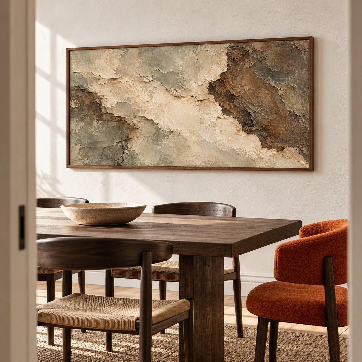 Right-oblique view of a textured abstract painting above a dark wood dining table with sculptural dark chairs and light plaster walls.