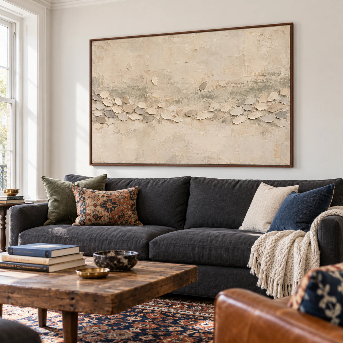 Chalk Procession displayed above a charcoal linen sofa in a bright living room with pale walls and daylight.