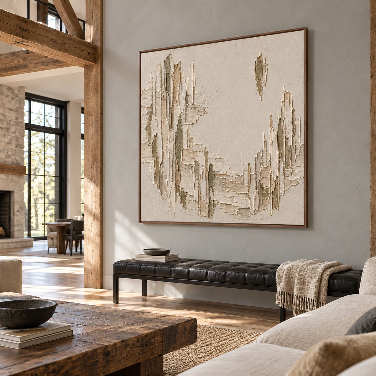 Right-oblique view of a square textured painting in an expansive lounge with tall windows, a black leather bench and cool gray walls.