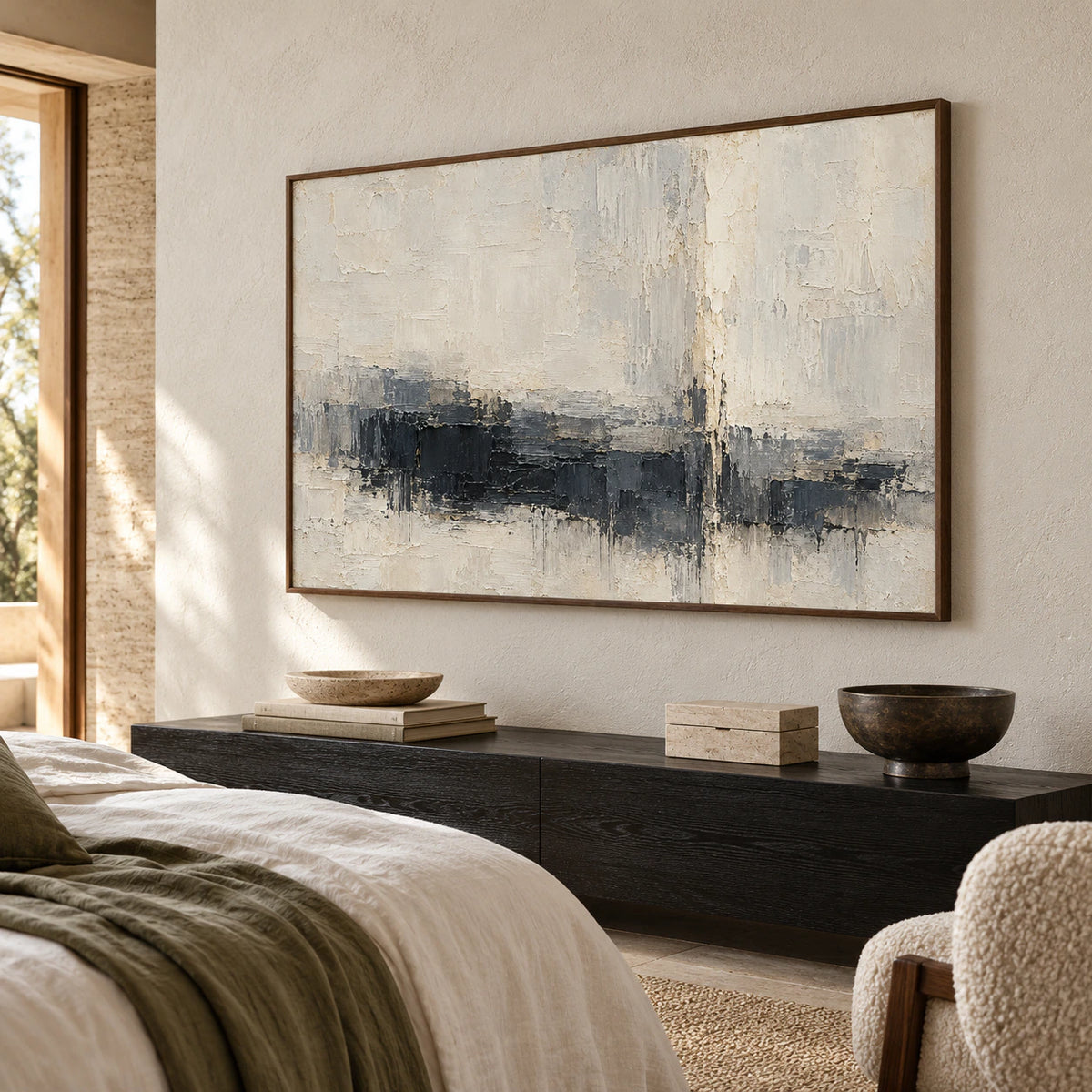 Charcoal and ivory abstract painting above a low black-stained wood bedside console, with white linen and muted sage accents, viewed from a slightly low left angle.