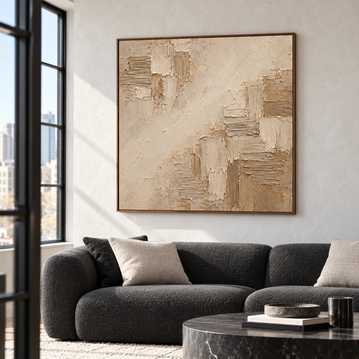 Square abstract artwork as the focal point above a charcoal sofa in a bright living room with pale walls and natural daylight.