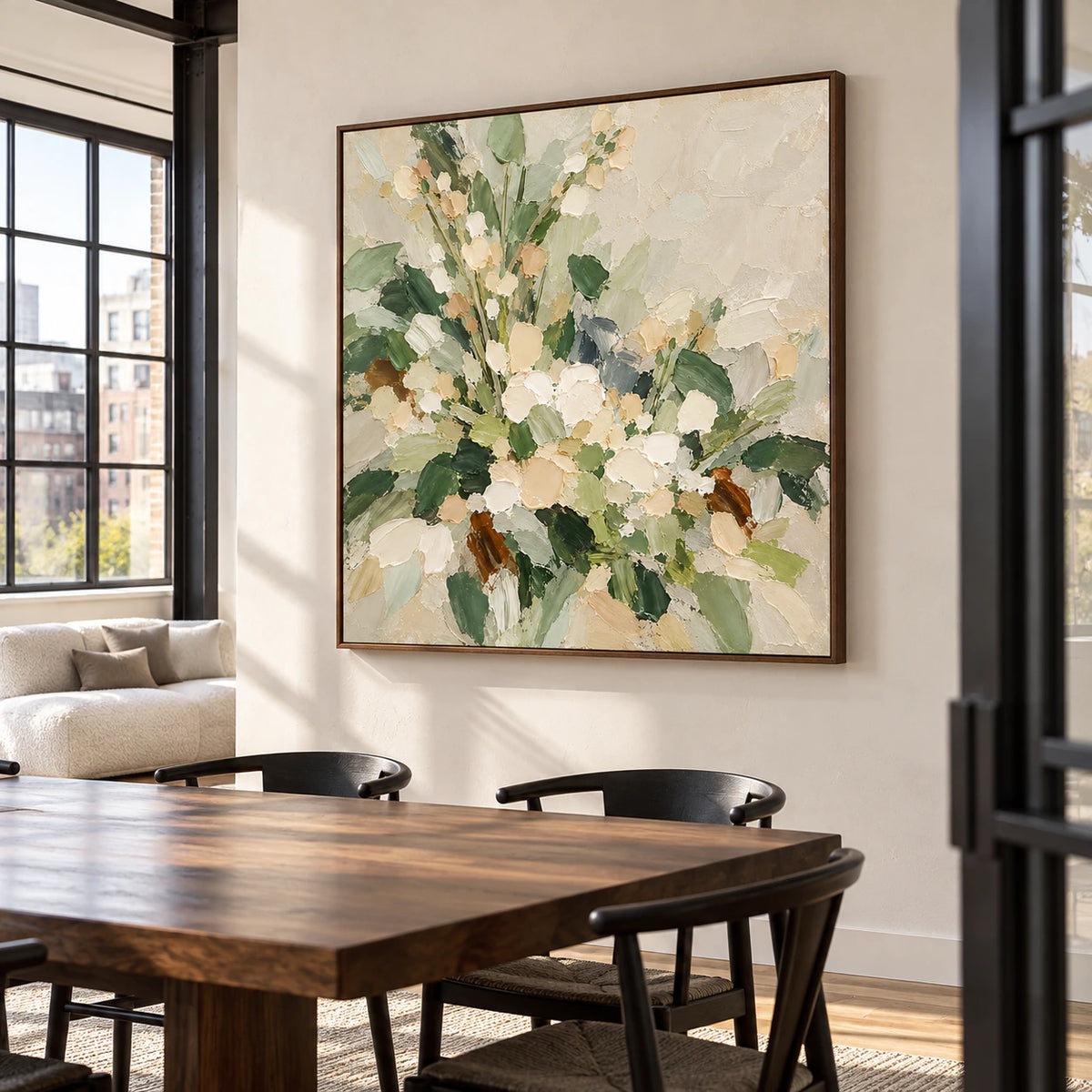 Square floral painting centered on a dining room wall above a long table in soft daylight.