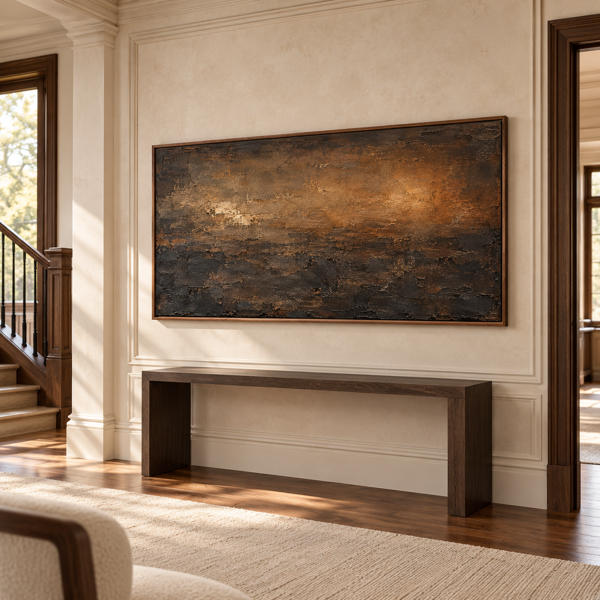 Wide brown and ochre abstract painting on a pale limestone foyer wall above a dark console, viewed from a slightly elevated left angle.