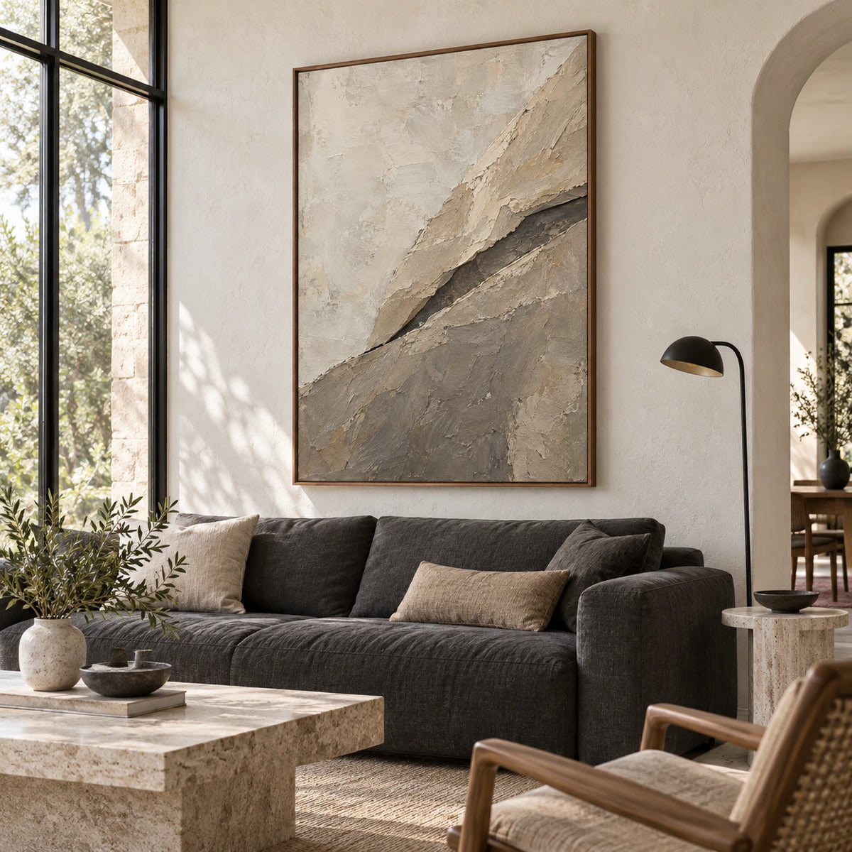 Large vertical textured abstract painting above a sculptural sofa in a bright living room.