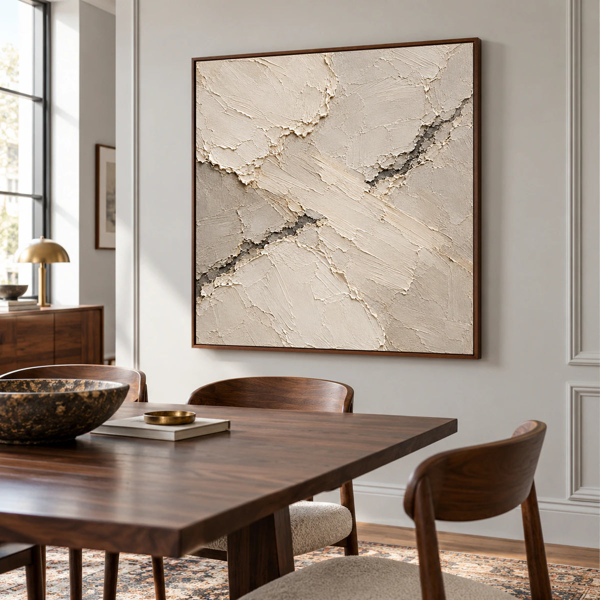Square abstract artwork anchoring a refined dining room, seen from a slight left angle above a dark wood dining table with light-filled windows.