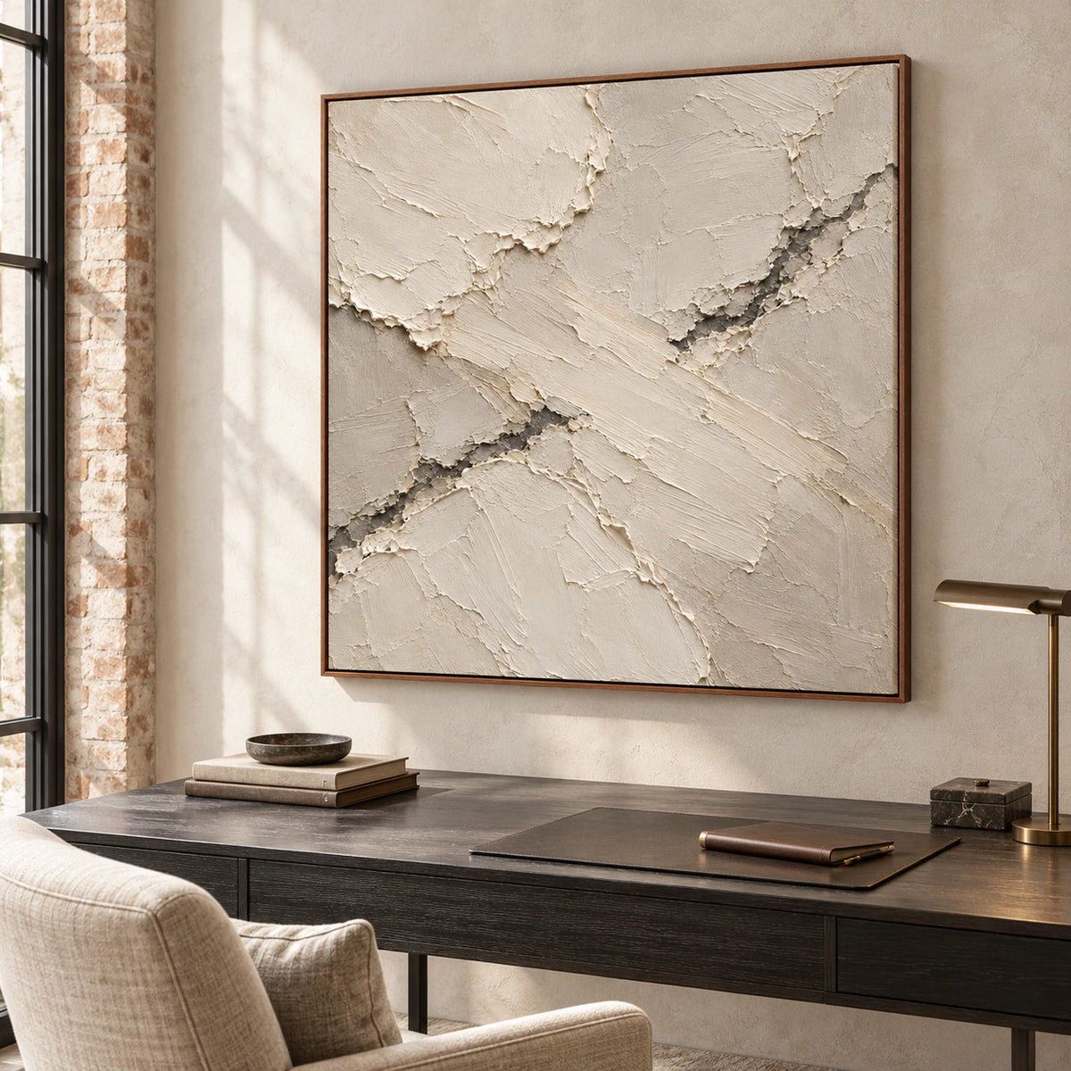 Large square textured abstract artwork in an airy home office reading nook, beside a charcoal desk and linen chair in clear daylight.