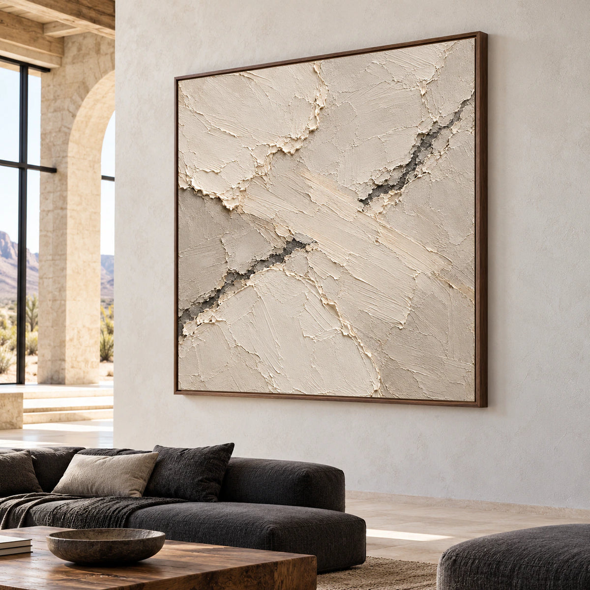 Large square ivory and taupe abstract artwork in an expansive loft lounge, framed by tall windows and restrained dark furnishings in bright natural light.