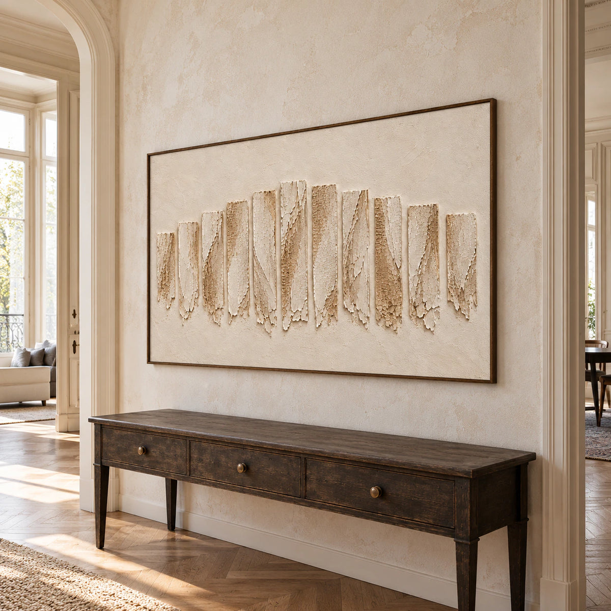 Large ivory textured painting on a pale stone foyer wall with a dark console and high ceiling, viewed from the left at a slightly low angle.