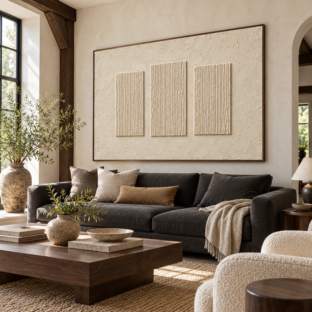 Ivory ribbed artwork above a charcoal sofa in a bright living room with pale walls and walnut accents, viewed from a slight left angle.