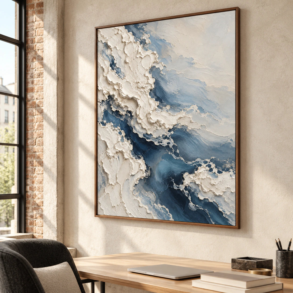 A large abstract artwork brings tactile detail to an airy home office with a simple desk, pale plaster walls and clear daylight.