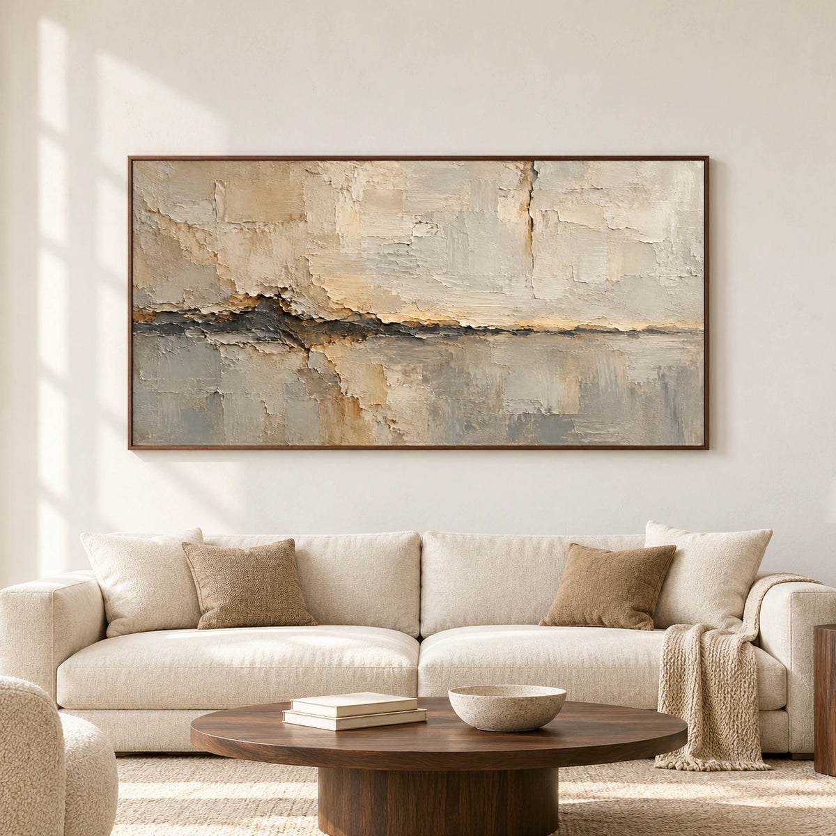 Large horizontal abstract artwork with ivory, sand and charcoal textures displayed prominently on a pale wall in a spacious, softly lit room.