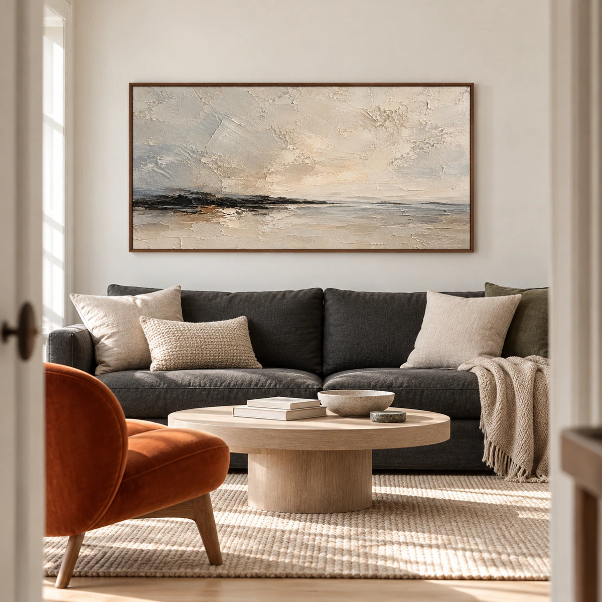 Gesso-Littoral painting above a deep neutral sofa in a bright, open living room with pale walls and restrained furnishings.