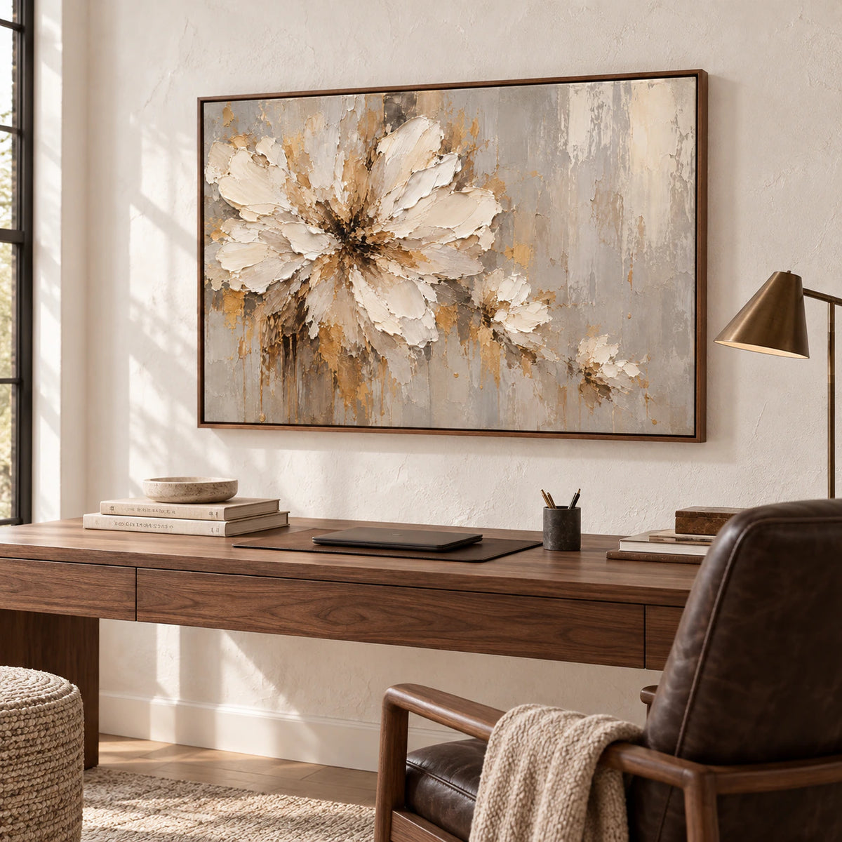 Textured floral artwork above a simple desk in an airy home office with restrained furnishings and daylight.
