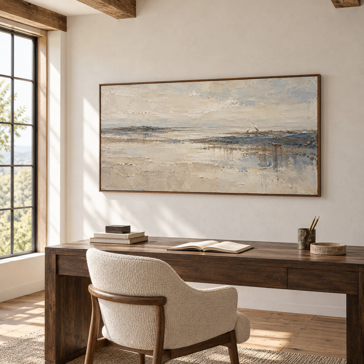 Heron shoreline painting above a dark wood desk in an airy home office with pale walls, a tall window and a sculptural chair, viewed from the left.