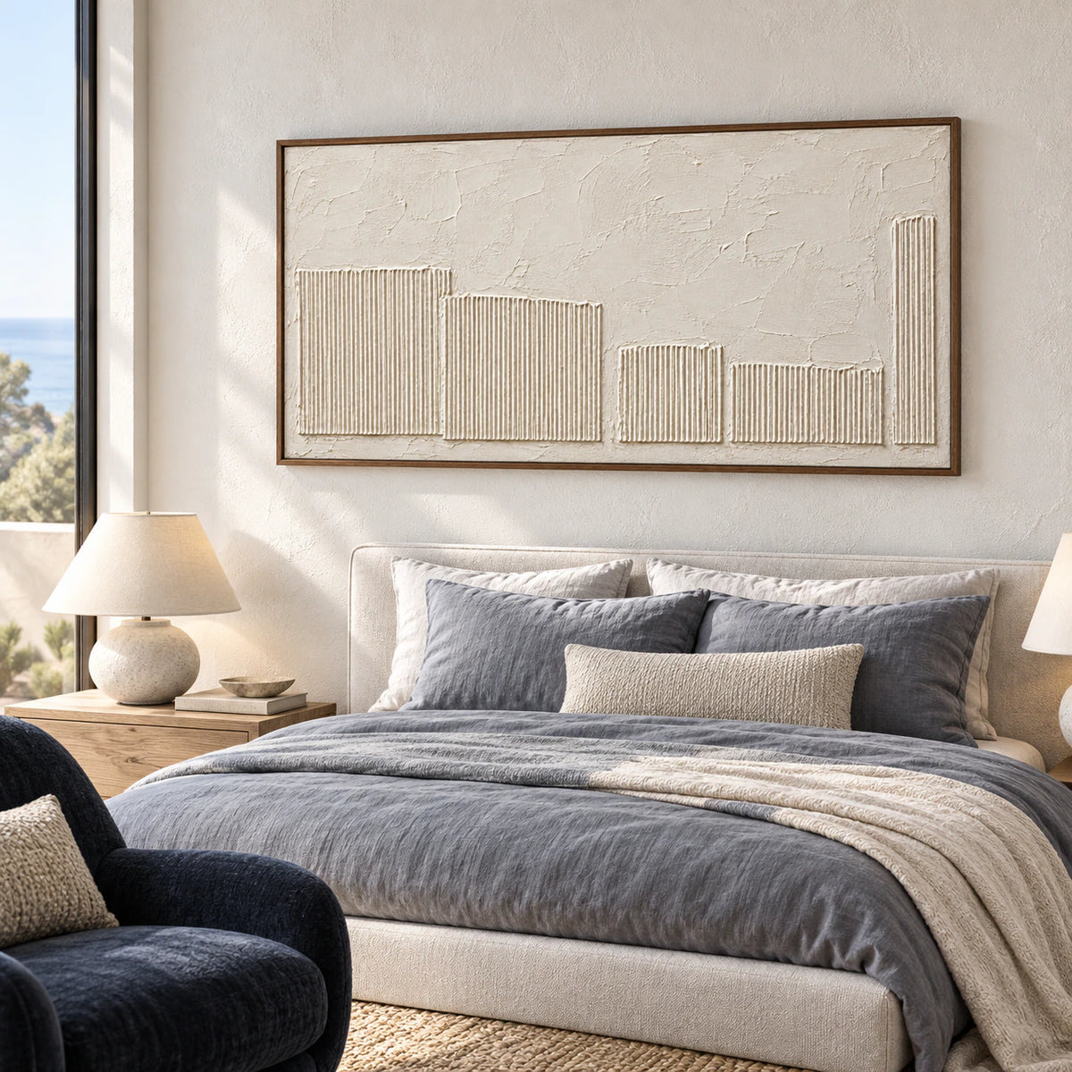 Ivory textured painting above a low bed with muted slate bedding, viewed from a slight right angle in a softly daylit bedroom.