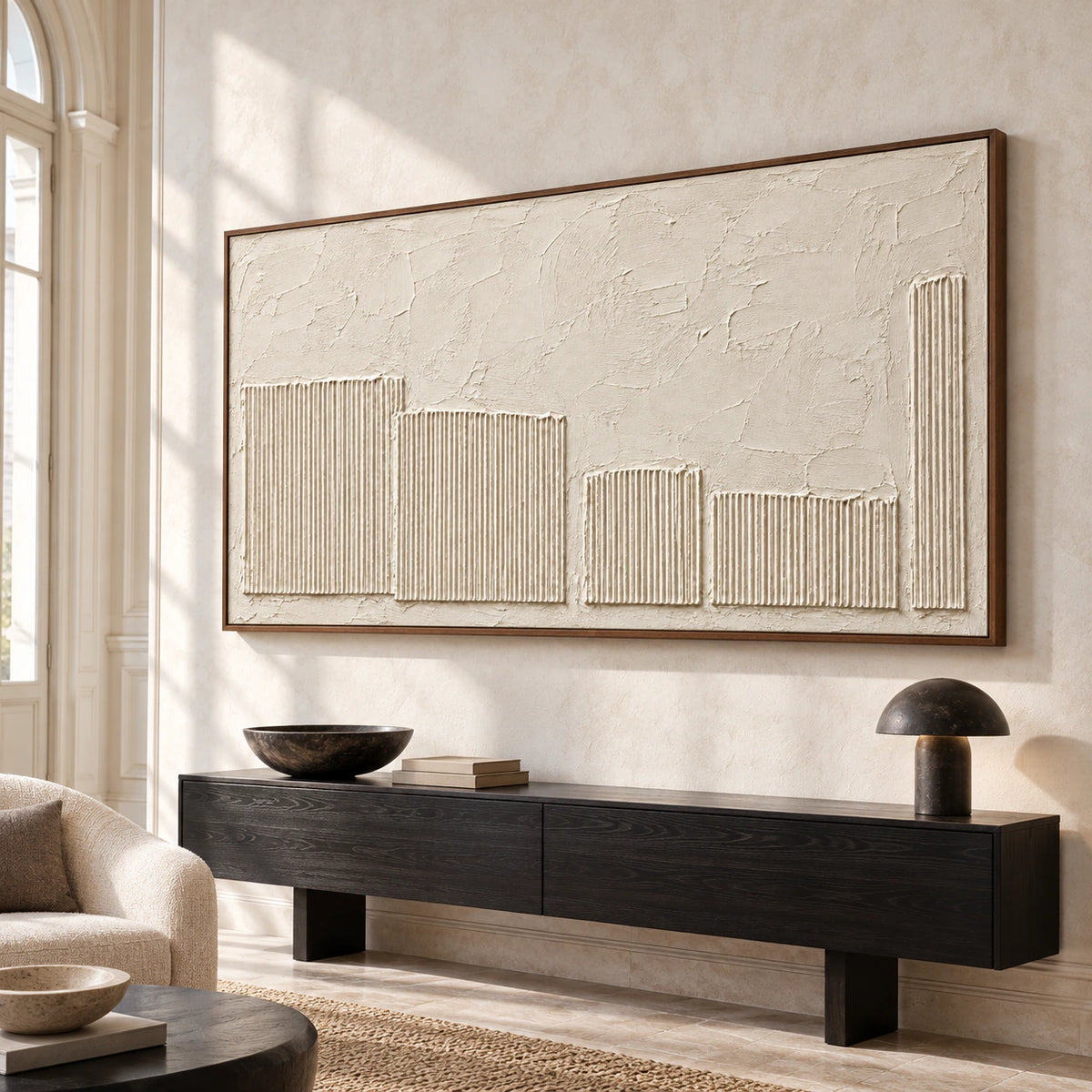 Ivory textured painting on a tall pale stone wall above a black console in a bright foyer, viewed from a low, slightly left angle.