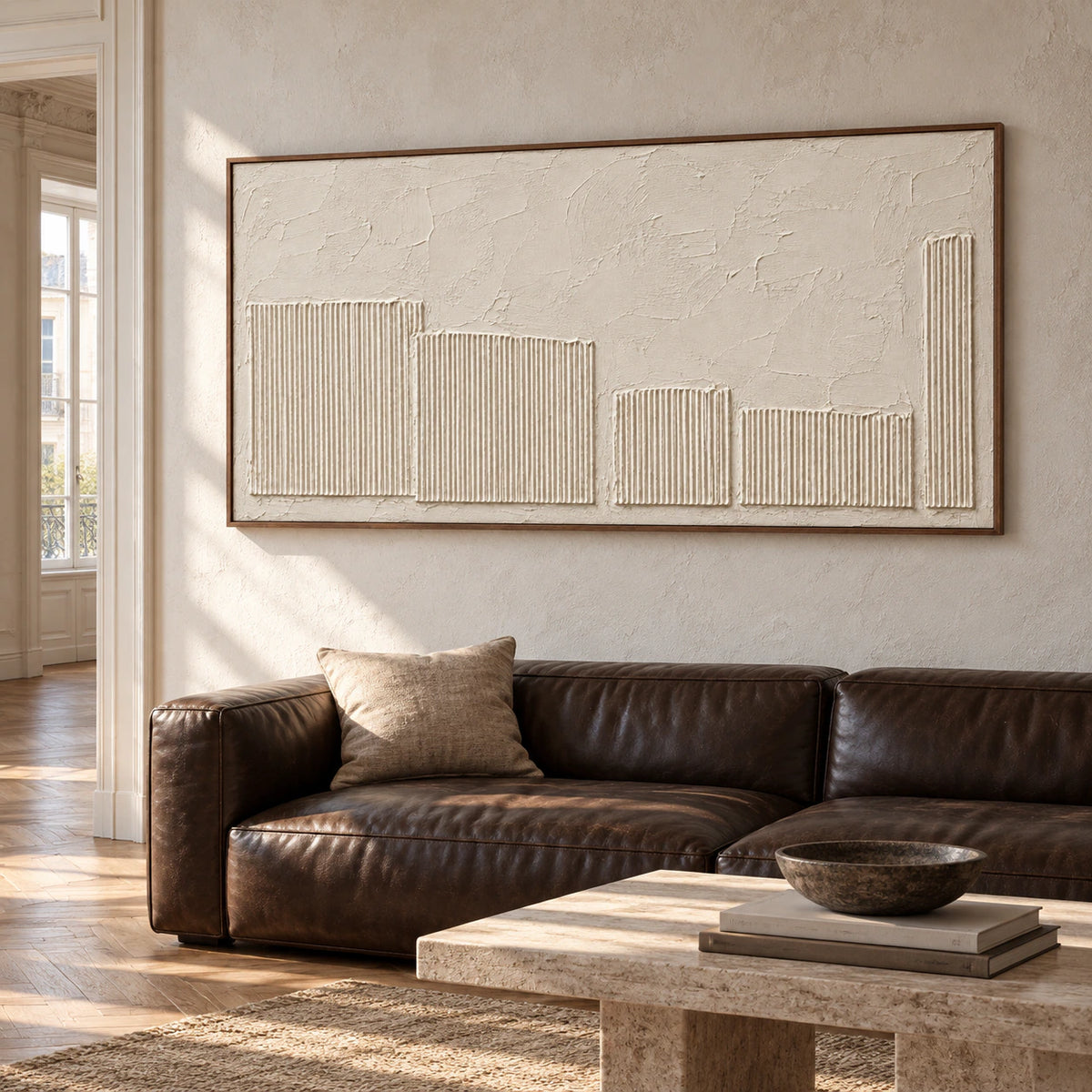Ivory textured painting on a broad wall in an expansive, naturally lit loft interior with dark leather seating, viewed from a slight right angle.