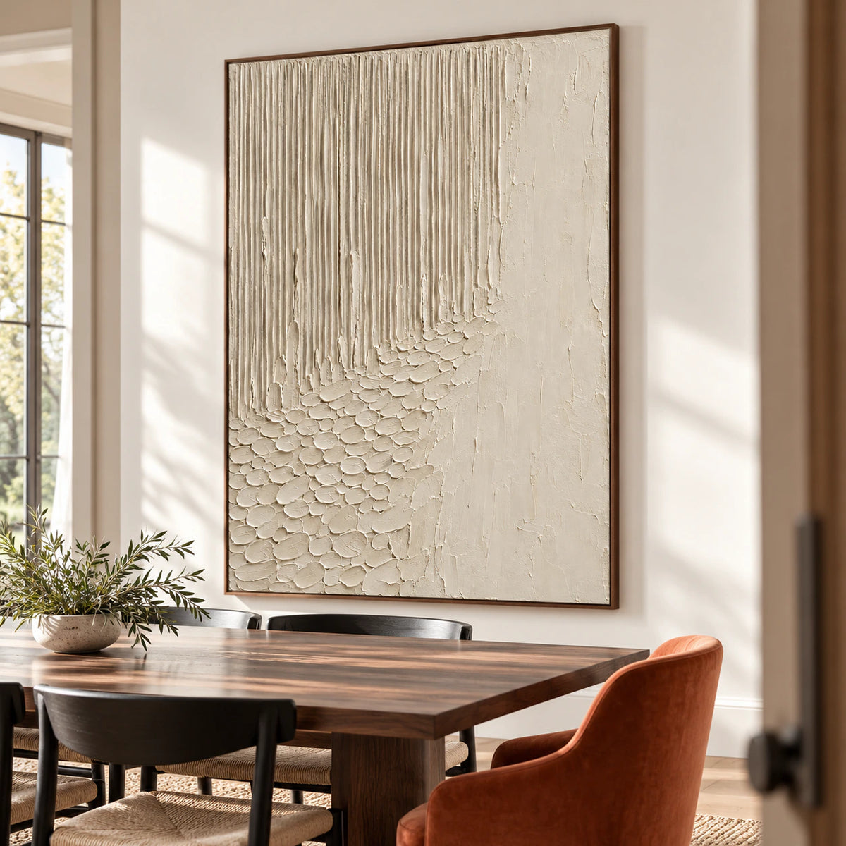 Ivory-Cascade oil painting on a warm white wall beyond a long dark walnut dining table with black chairs and greenery, viewed from the right.
