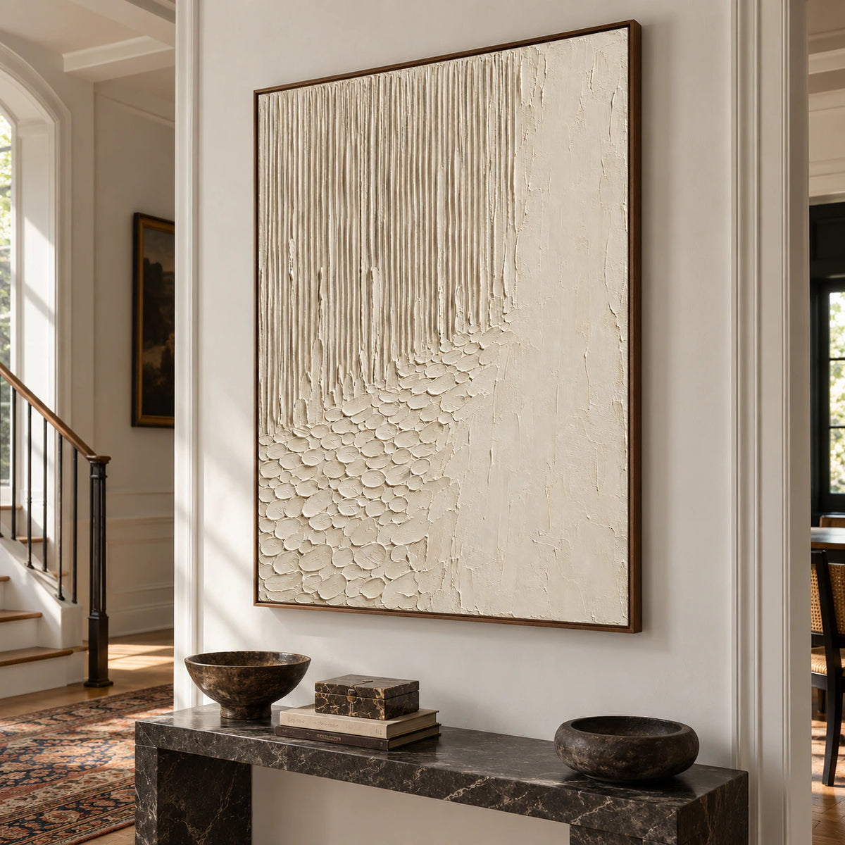 Ivory-Cascade oil painting above a dark stone console on a tall, bright foyer wall, viewed from a slight left angle at a low viewpoint.
