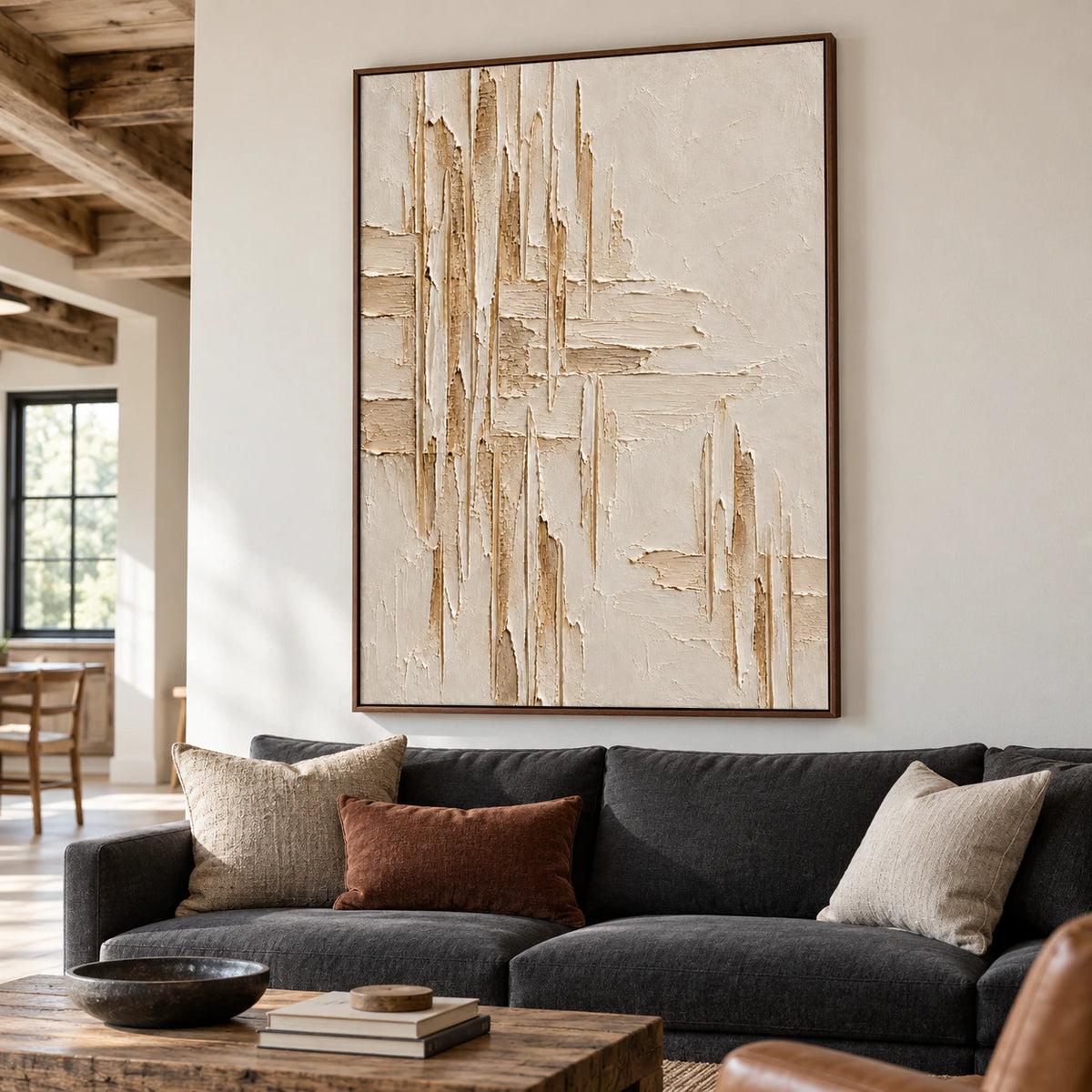 Large vertical ivory textured painting above a charcoal sofa in a bright living room, viewed from the left at seated eye level.