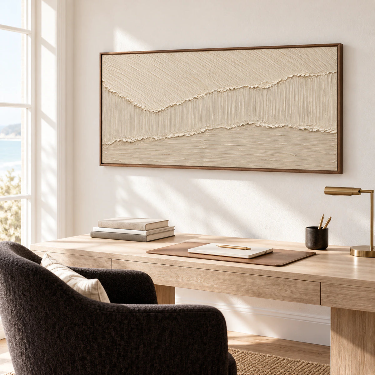 Large ivory and beige abstract artwork above a desk in an airy home office with pale walls and restrained dark furnishings.