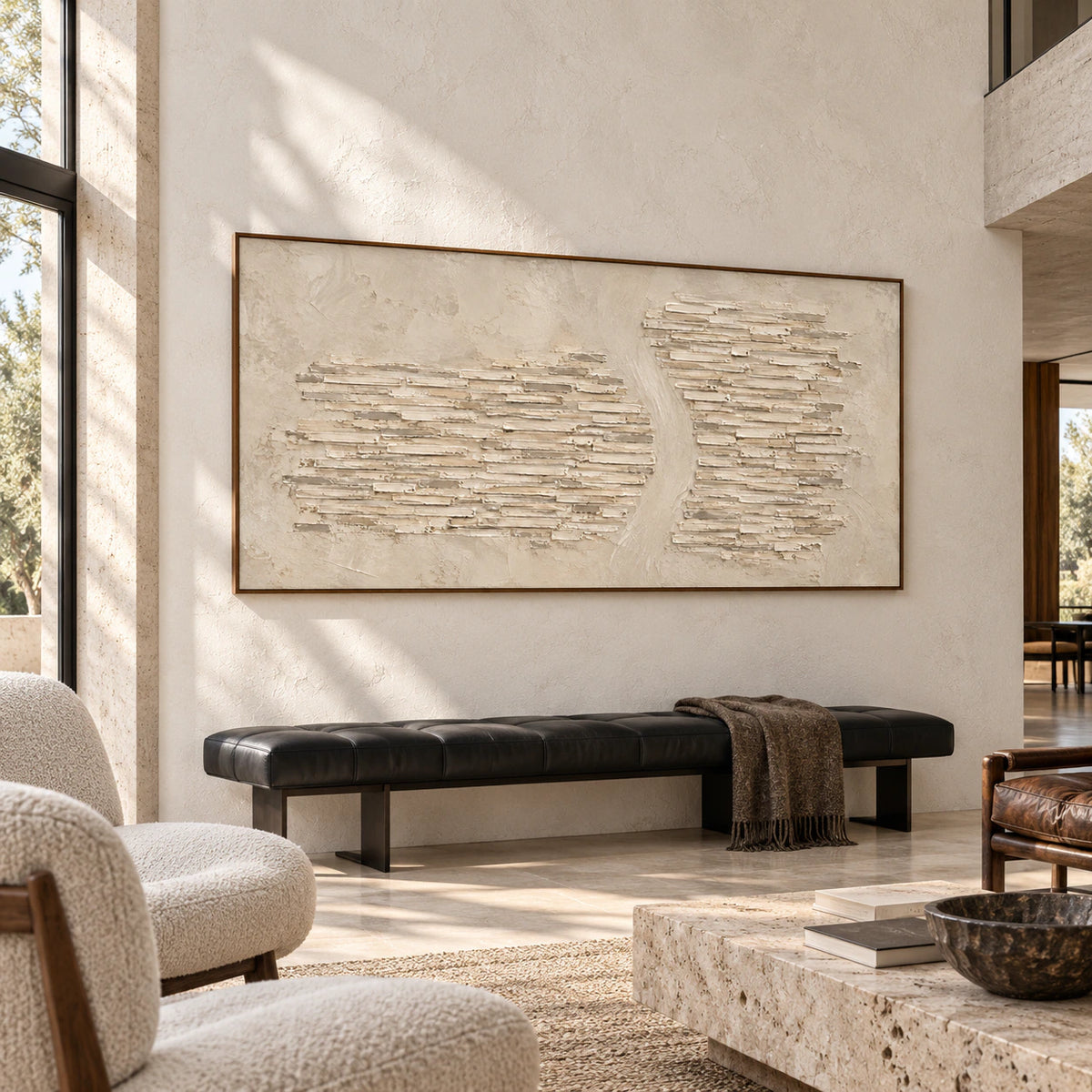 Limestone-Cadence on a pale concrete wall above a low black leather bench in a sunlit double-height interior, viewed from the right.
