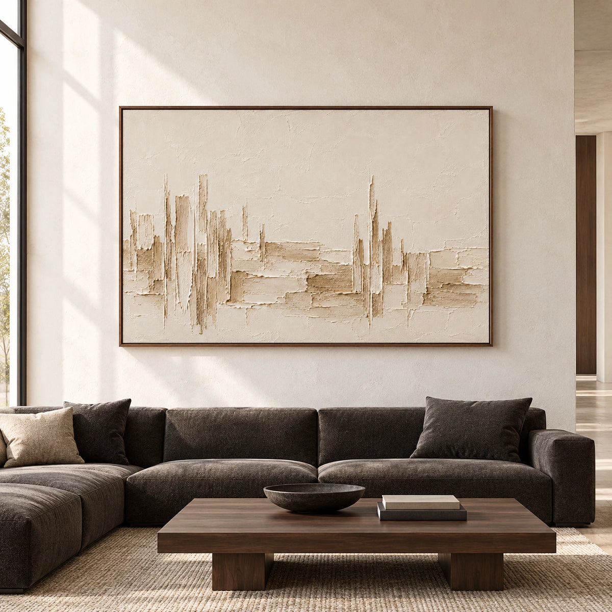 Straight-on view of a large ivory textured painting on a pale stone wall in a spacious, daylit living room with dark wood and charcoal furnishings.