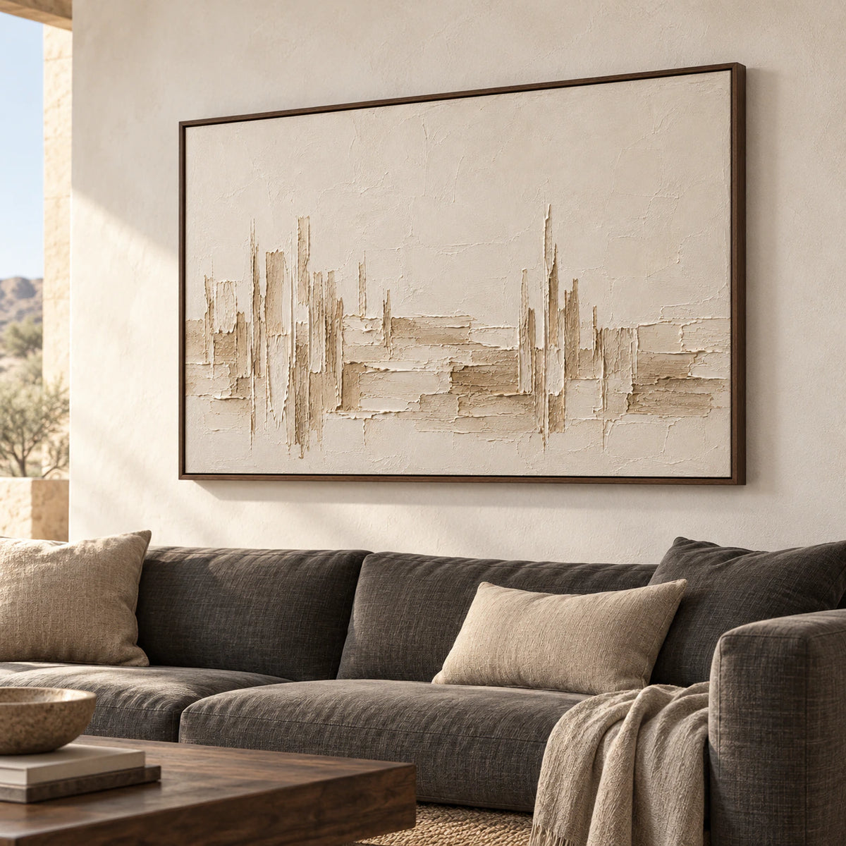Ivory textured painting above a charcoal sofa, viewed slightly from the left in a bright living room with pale walls and a low dark wood table.