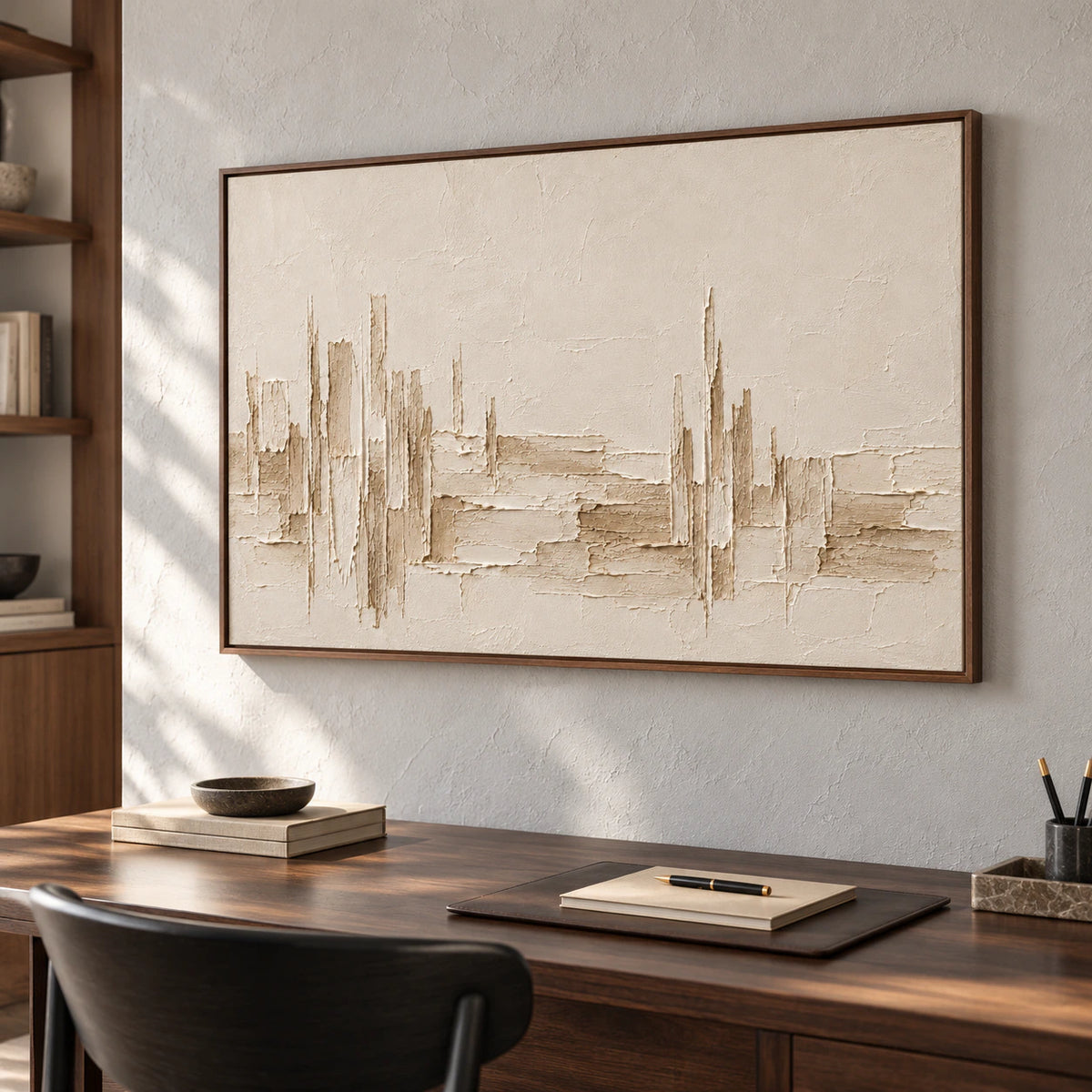 Ivory textured painting above a dark writing desk on a pale gray wall, viewed from the right in a daylit office with a black chair and sparse shelving.