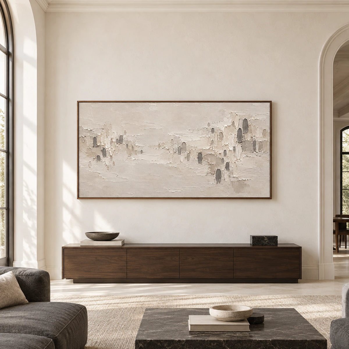 Large horizontal abstract painting with warm ivory ridges and scattered charcoal marks displayed prominently on a light gallery wall in a spacious room.