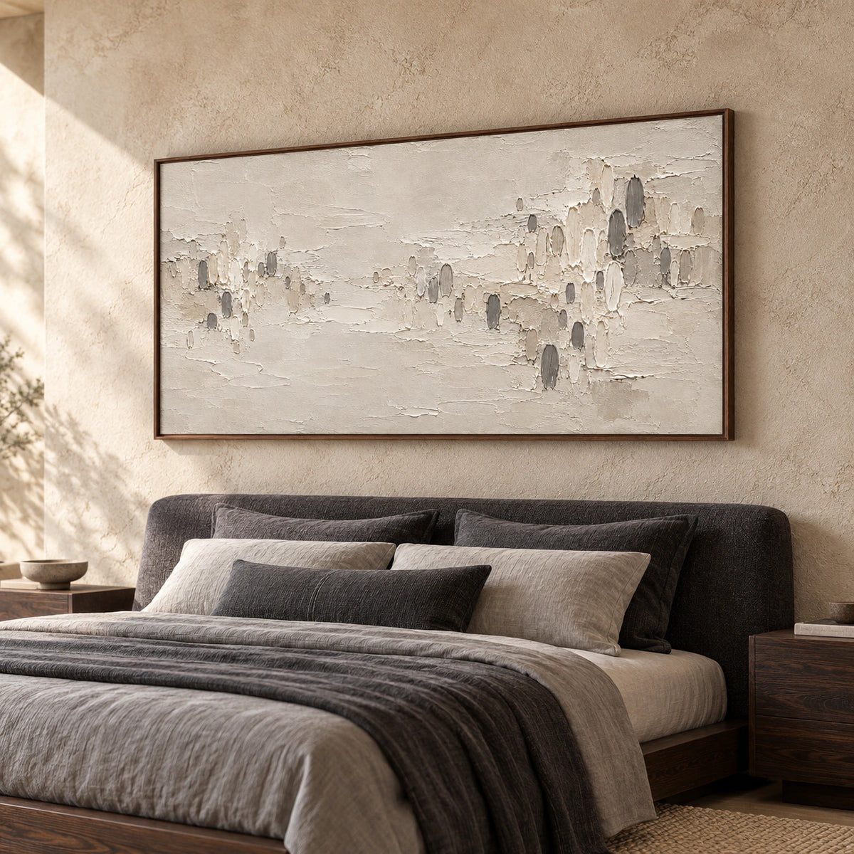 Wide tactile abstract painting in warm ivory, taupe and charcoal above a low bed in a quiet, daylight-filled bedroom.