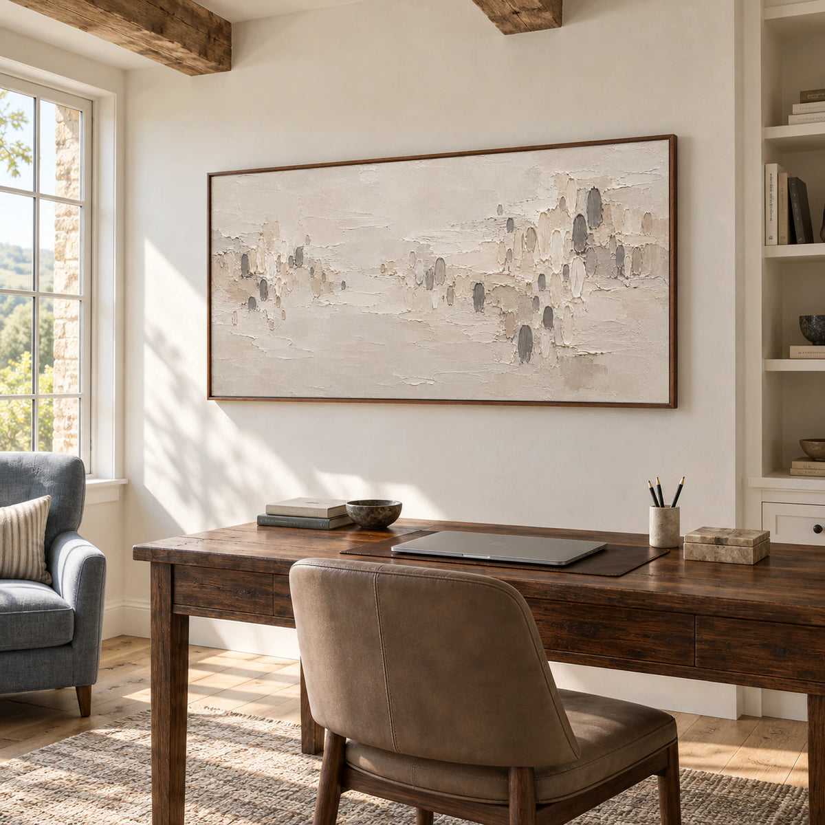 Large horizontal ridged abstract painting on a pale wall in an airy home office with a dark wood desk and generous daylight.