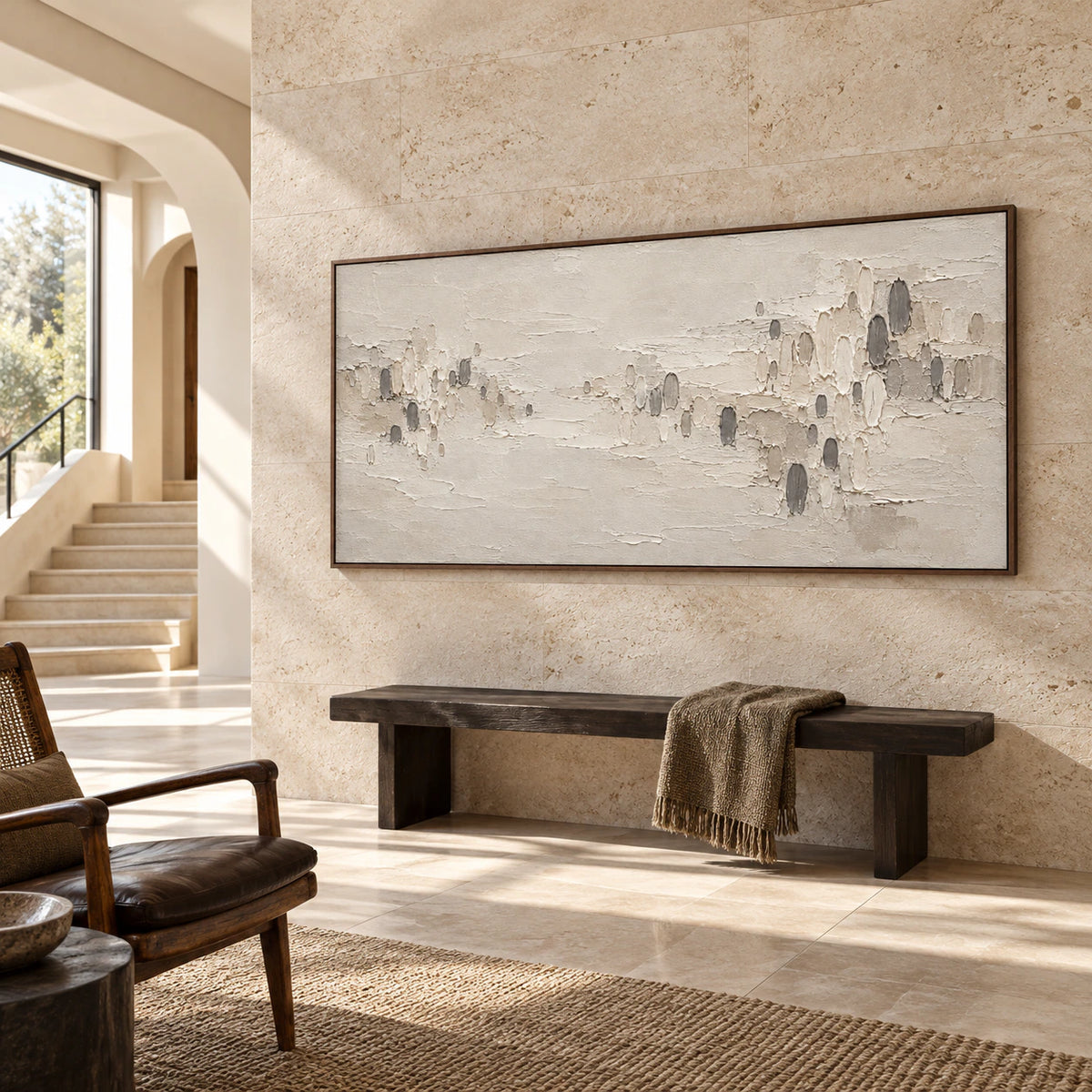 Oversized ivory and charcoal abstract painting anchoring a bright gallery-scale foyer with stone flooring and a sculptural bench.