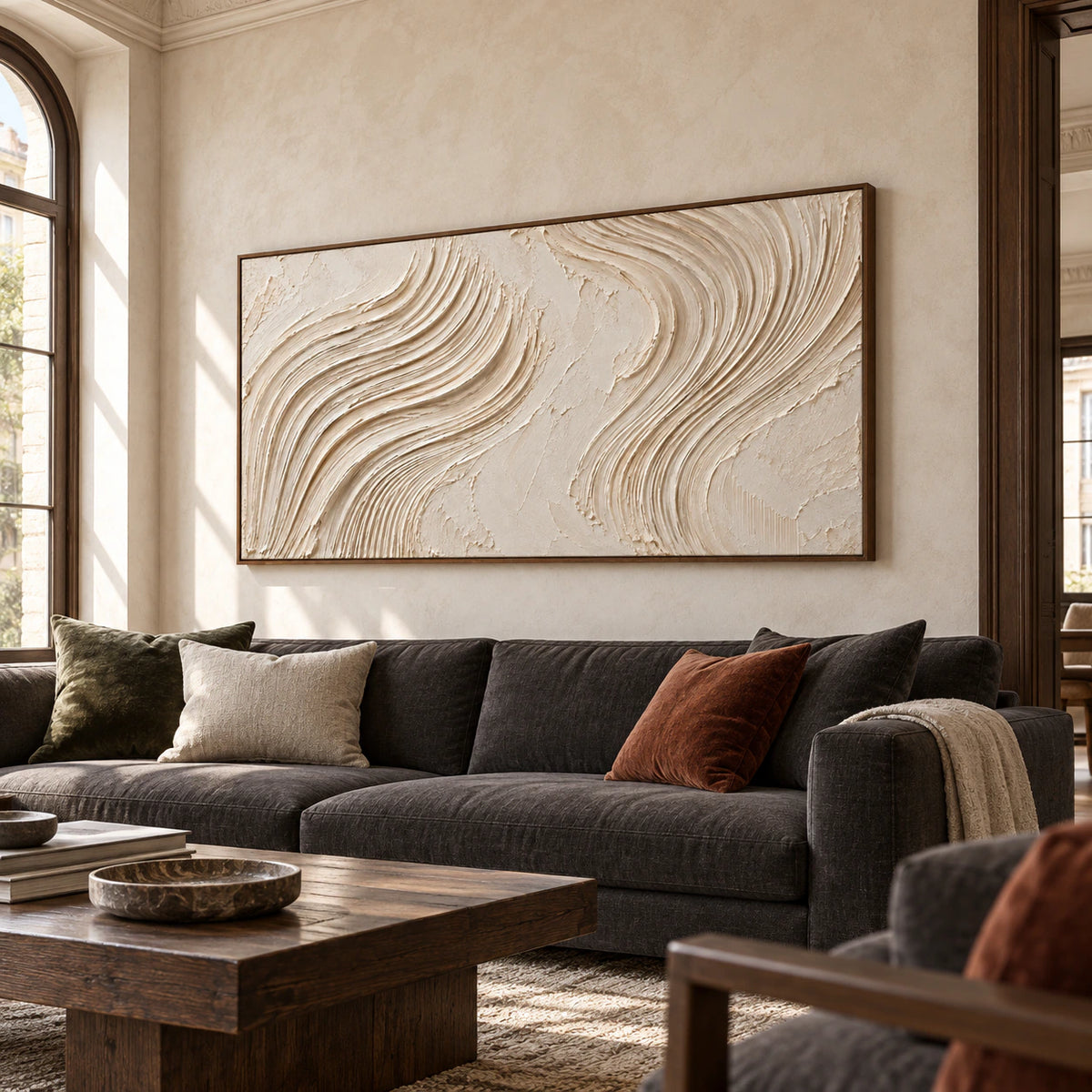 Large ivory textured abstract artwork above a charcoal sofa in a bright, open living room with natural daylight.