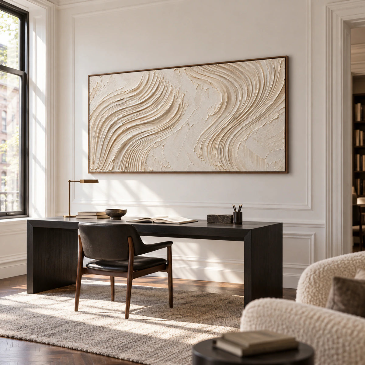 Large textured ivory abstract artwork above a simple desk in an airy home office and reading space.