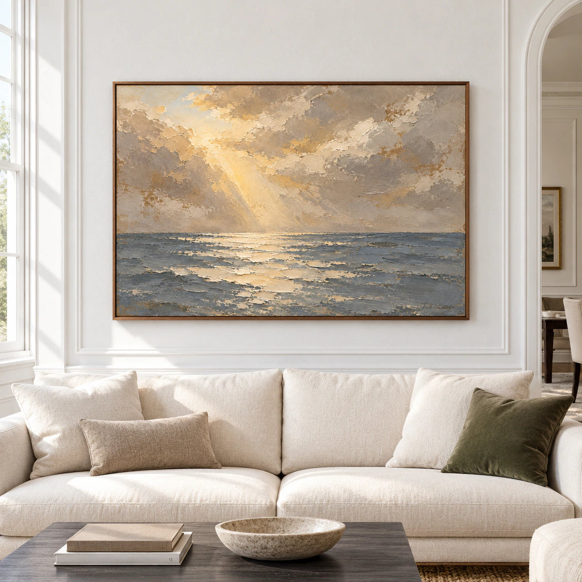 Large horizontal seascape oil painting viewed straight on in a spacious, bright living room, with slate-blue water and warm ivory clouds.