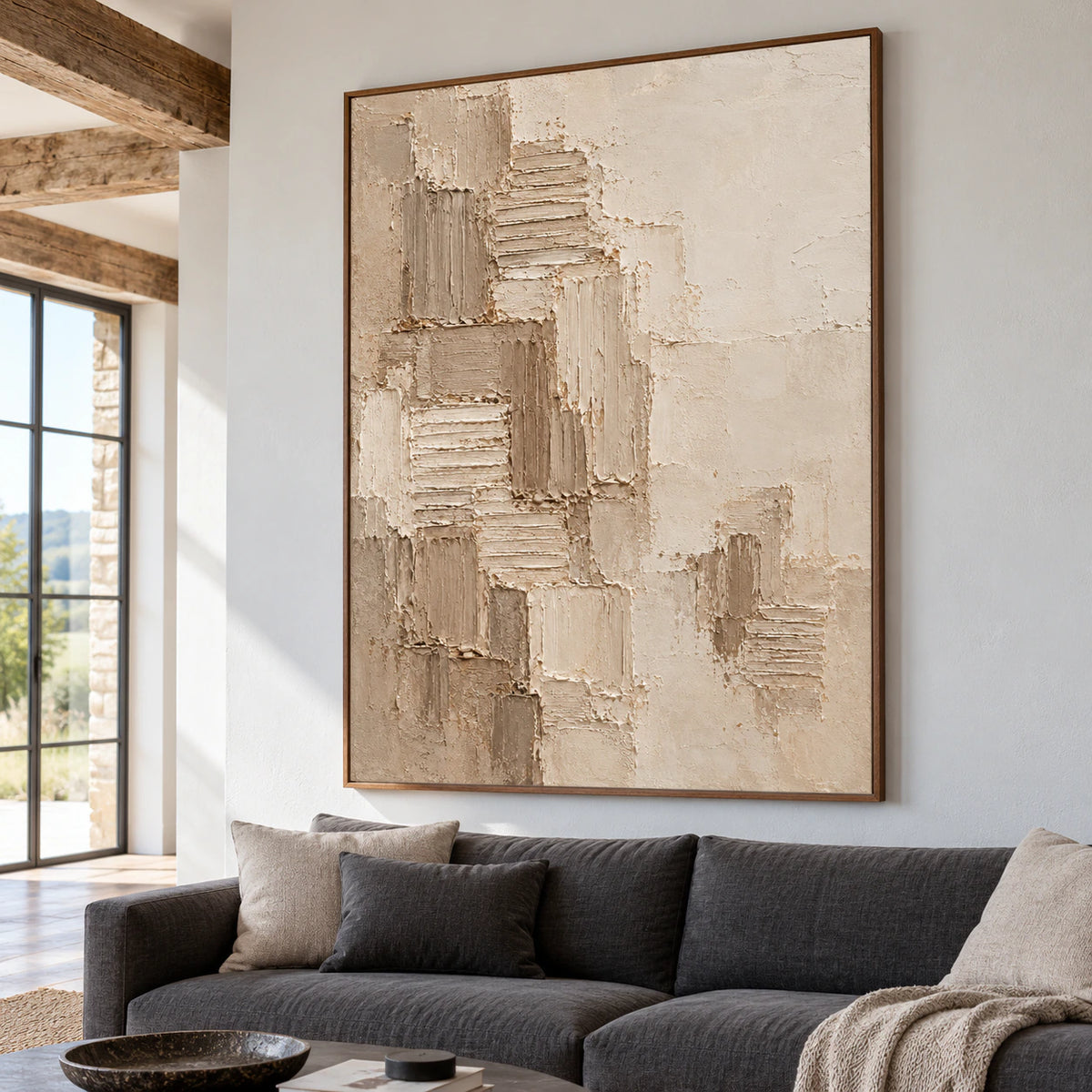 Large vertical abstract painting above a low charcoal sofa in a bright living room.