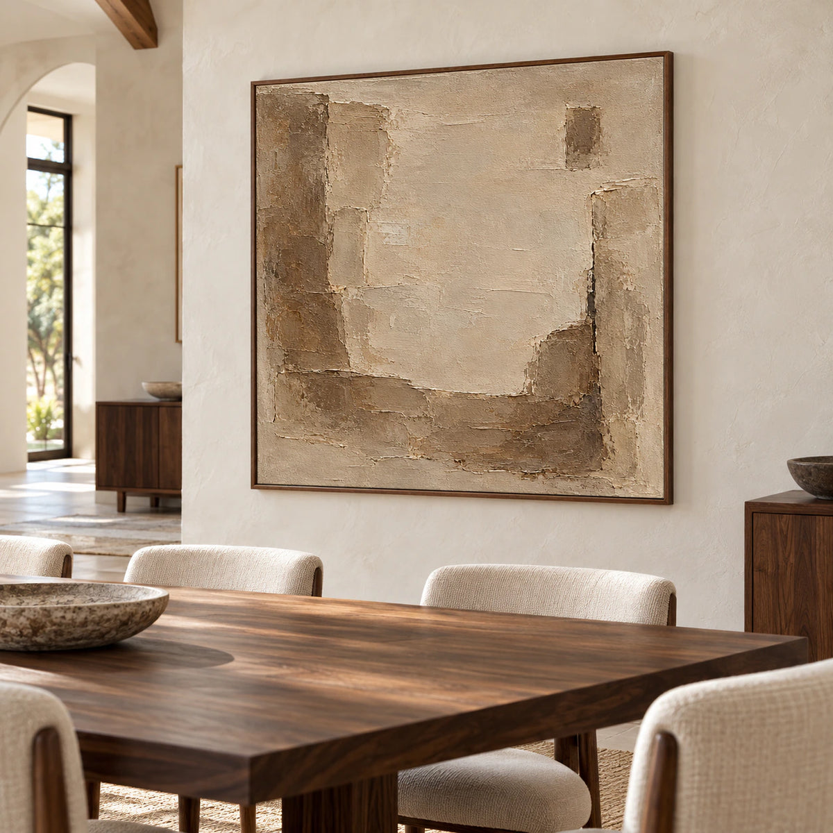 Square abstract painting as the focal point of a refined dining room with a long table and natural daylight.