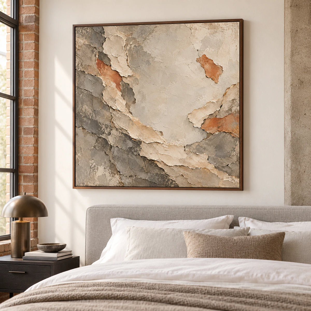 Marl-Unfurl painting on a warm white bedroom wall with a pale gray upholstered bed, white linen and an ink-toned bedside table, viewed from the right near the foot of the bed.