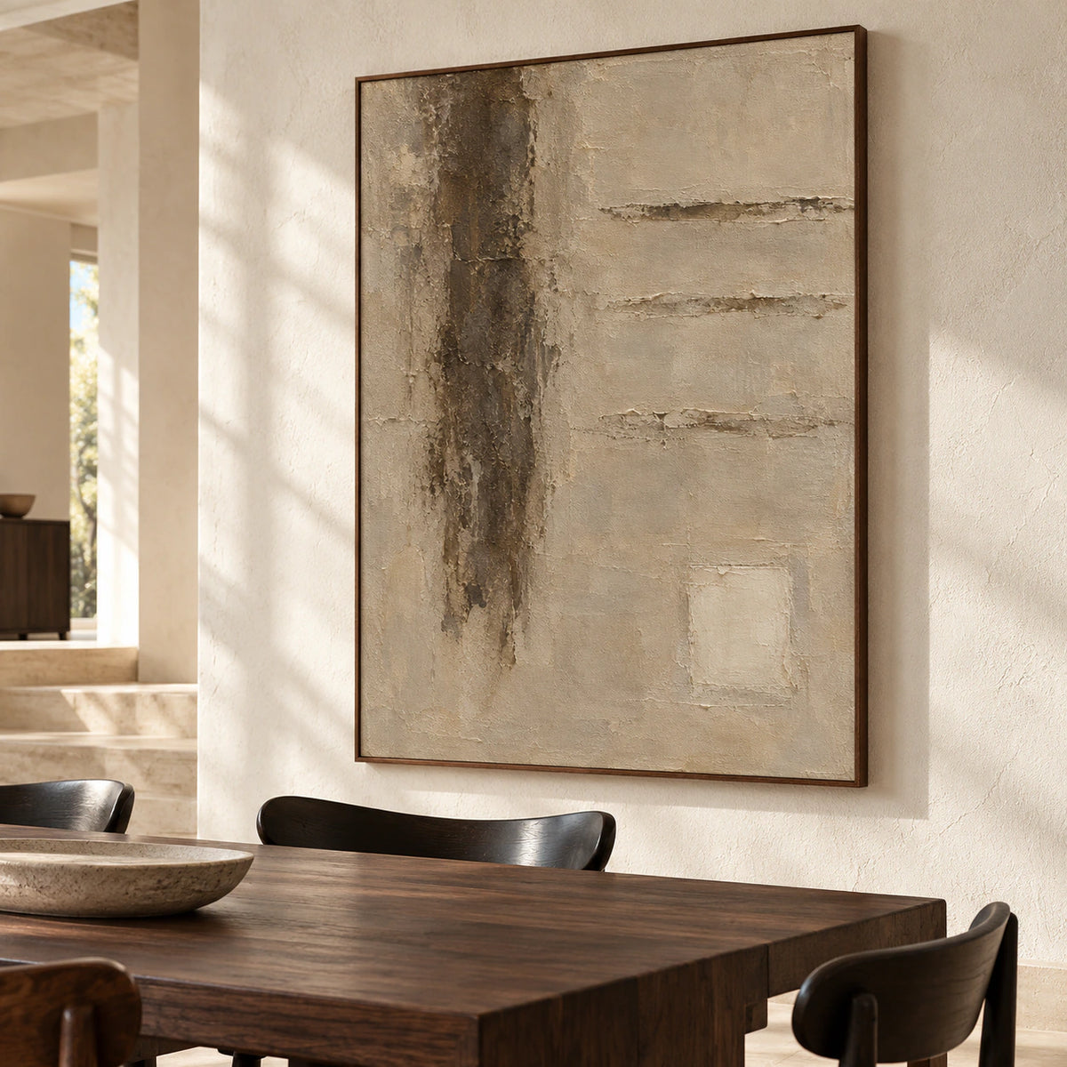 Vertical textured abstract painting on a pale limestone wall, viewed from the right in a bright dining room with a long dark wood table and black chairs.