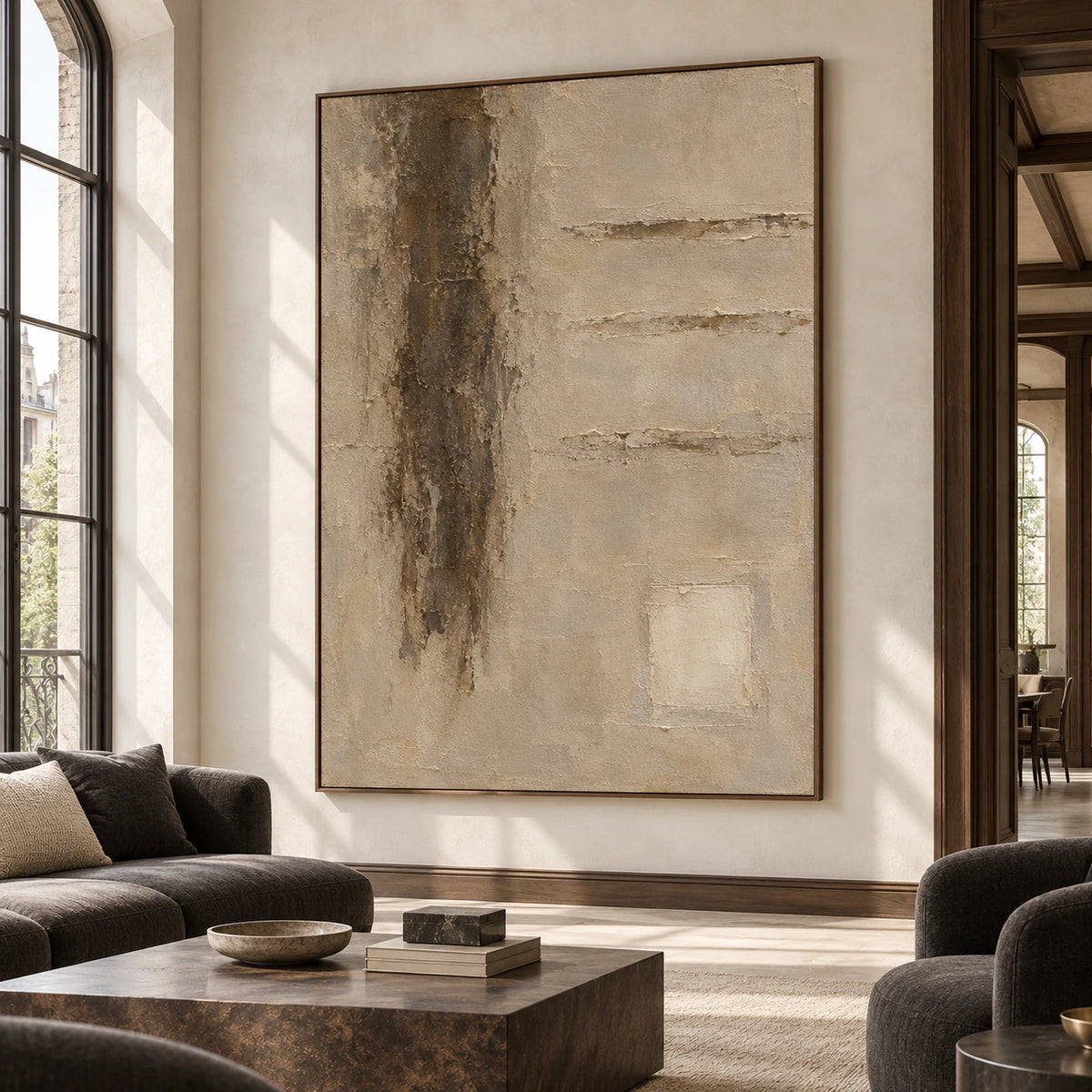 Large vertical textured abstract painting viewed from the right in an expansive lounge or loft with a pale wall, charcoal seating, dark timber and natural daylight.