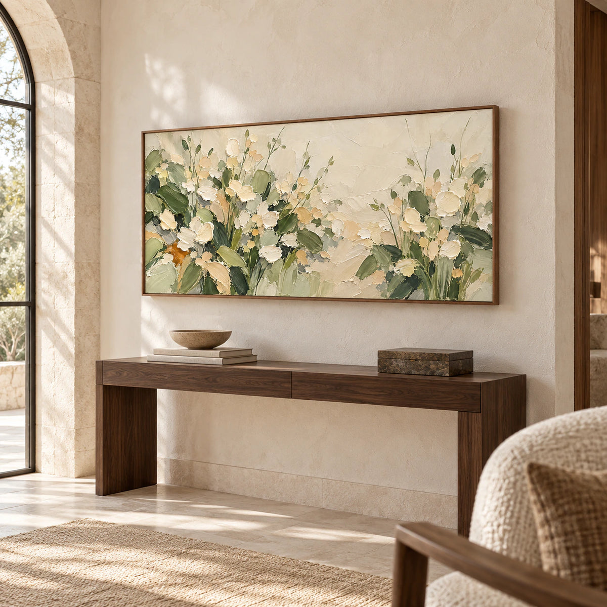 Large horizontal floral painting above a narrow dark console in a spacious foyer with tall limestone walls, viewed from a slight left angle.