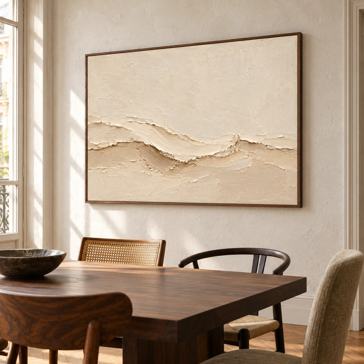 Warm ivory abstract painting on a light plaster wall above a dark walnut dining table and sculptural chairs, viewed from the right at standing height.