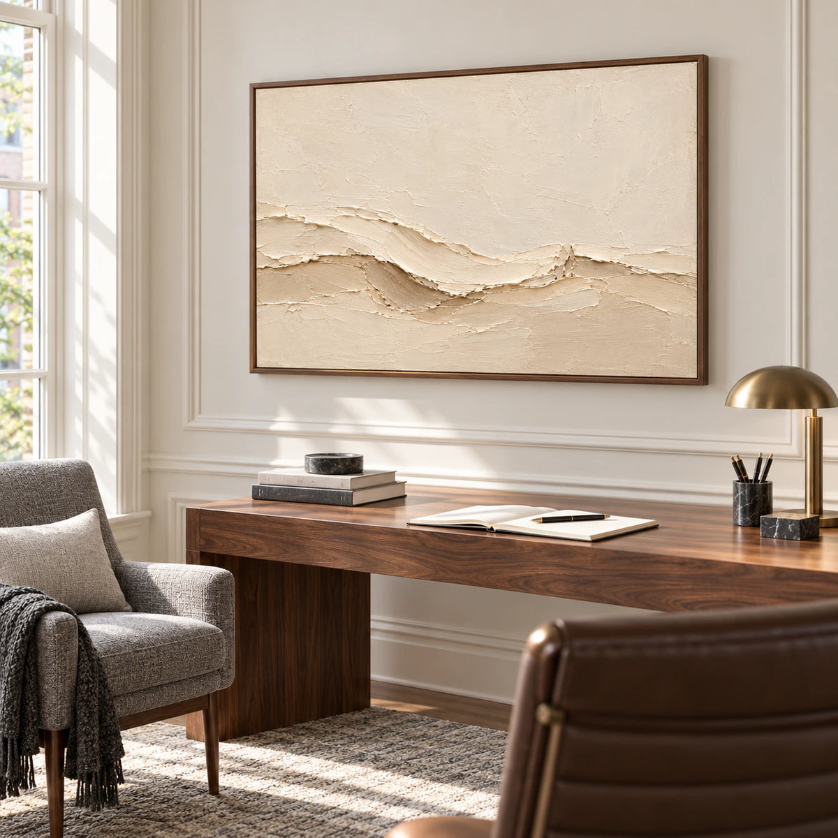 Warm ivory textured painting over a walnut desk beside a reading chair in a bright home office, viewed from a slightly elevated right angle.