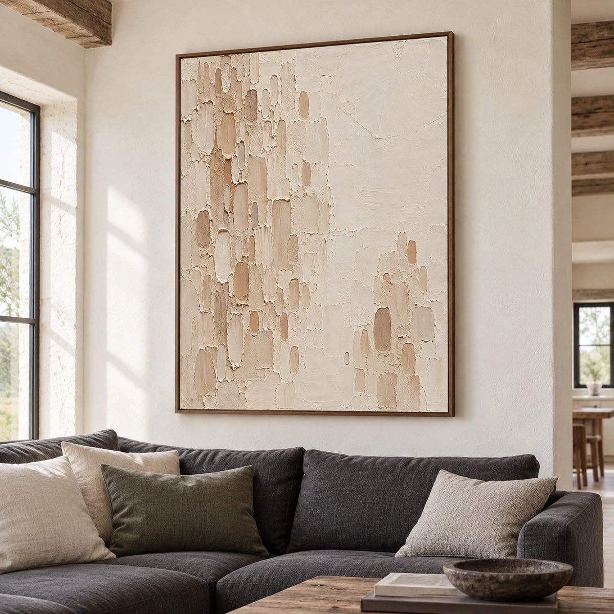 Large vertical Oatmeal-Recess painting above a charcoal linen sofa against a pale plaster wall, viewed from a slight left angle in a daylight-filled living room.