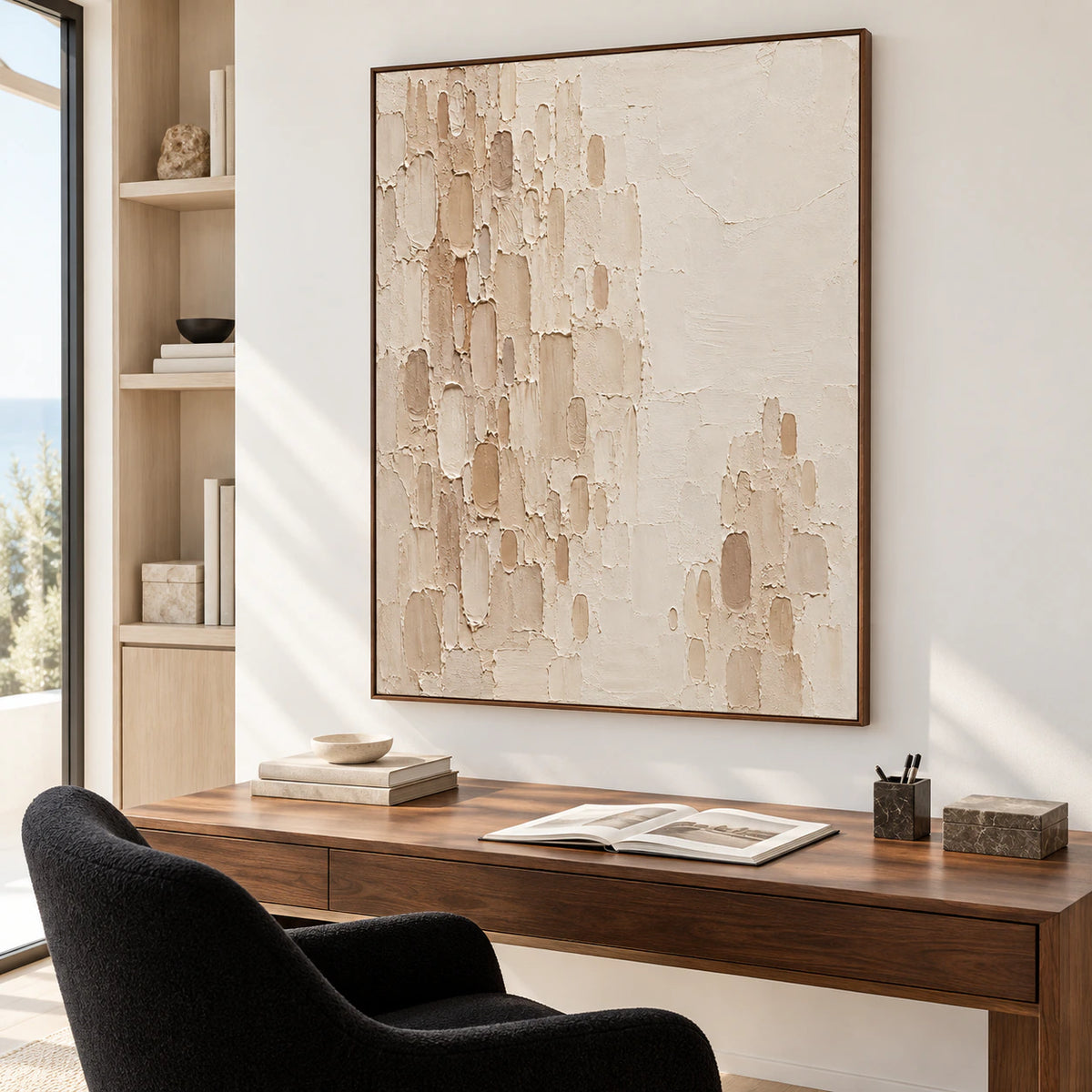 Large vertical Oatmeal-Recess painting above a walnut writing desk in a bright home office with a black reading chair and open shelving, viewed from the right.