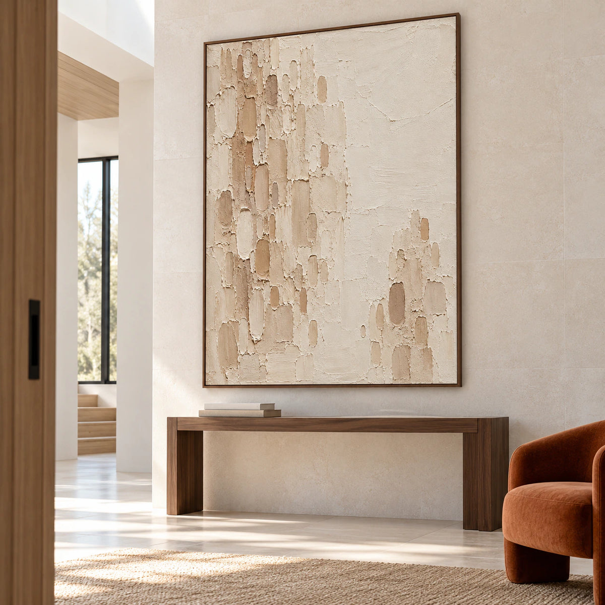 Large vertical Oatmeal-Recess painting above a slim dark console on a tall pale stone wall in a spacious, sunlit foyer, viewed from a low left angle.